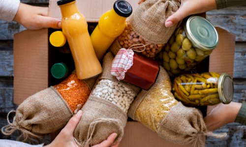 A cardboard box overflowing with juice and pantry items.