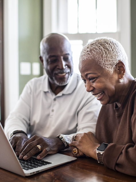 Smiling senior couple working on laptop