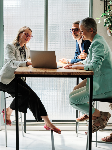 Middle age couple sitting at high top table looking at laptop with financial advisor