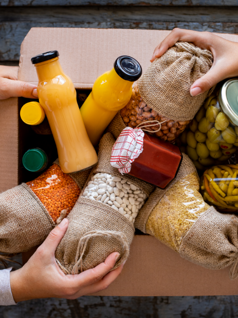 A cardboard box overflowing with juice and pantry items.