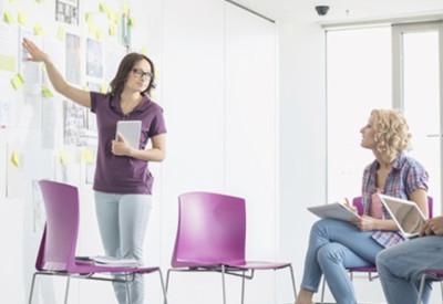 a woman presenting strategies on a white board