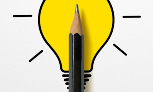 An illuminated lightbulb drawing with a small black pencil placed over it