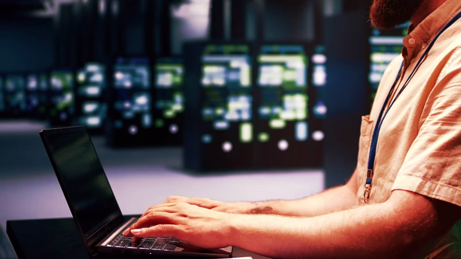 IT professional working on a laptop in a server room, representing backend infrastructure and management of web services.