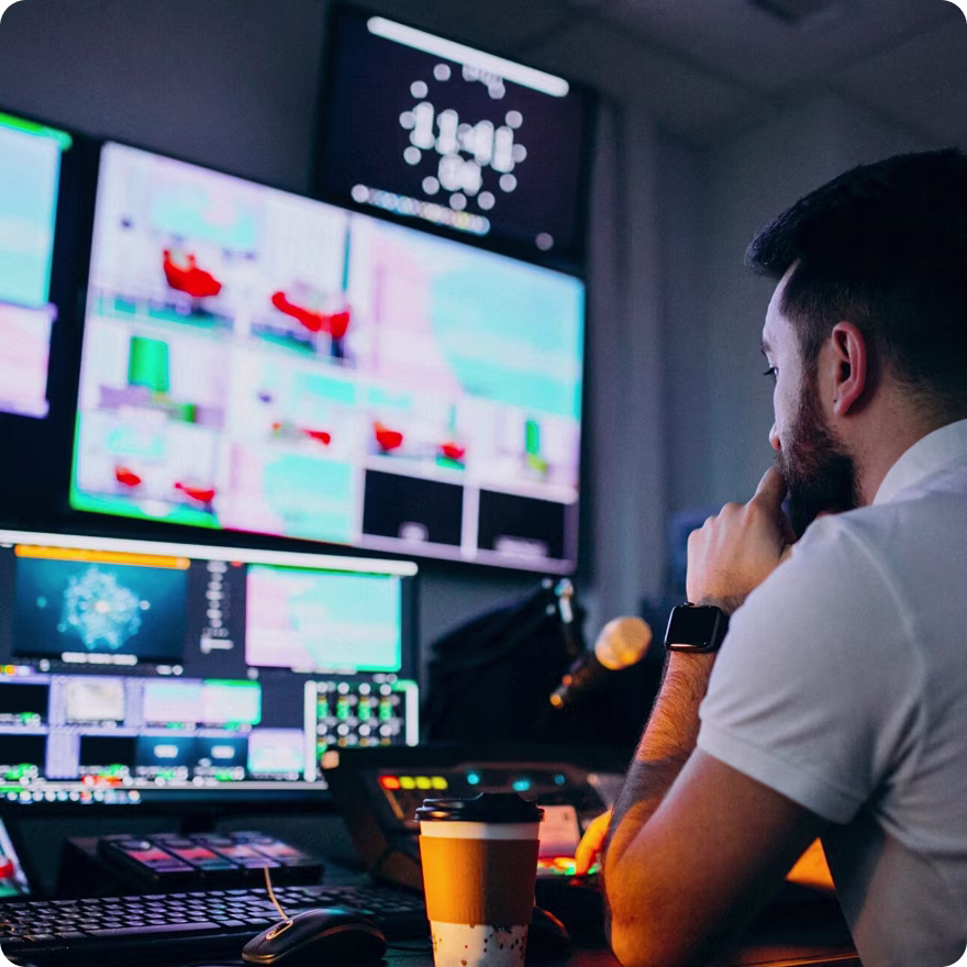 Man looking at monitors with a coffee near by Man looking at monitors with a coffee near by