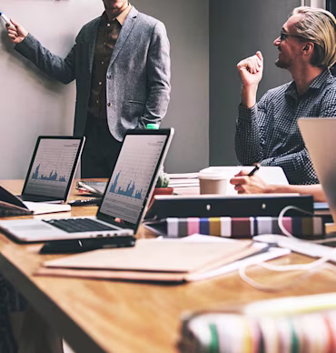 Team collaborating in a meeting with laptops displaying charts.