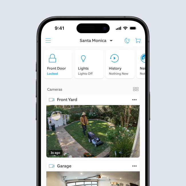 Smartphone screen displaying Ring app dashboard, showing live camera feeds of a person mowing a yard and the inside of a garage.