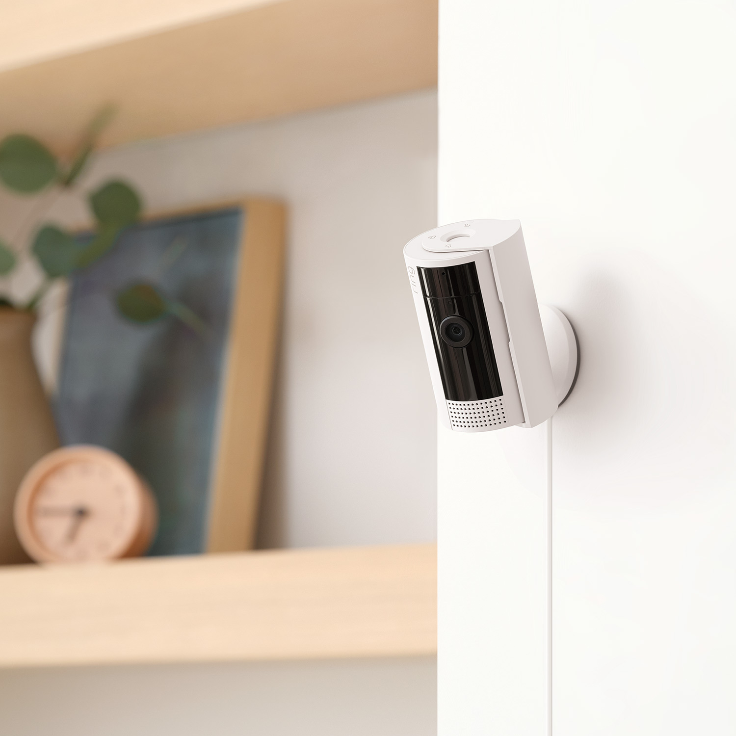 Inside Home Basic Kit (Indoor Cam + Alarm Security Kit, 5-Piece + Alarm Flood & Freeze Sensor) - White:Ring's indoor camera mounted on a wall looking into a well-lit room for Ring white Inside Home Basic Kit.