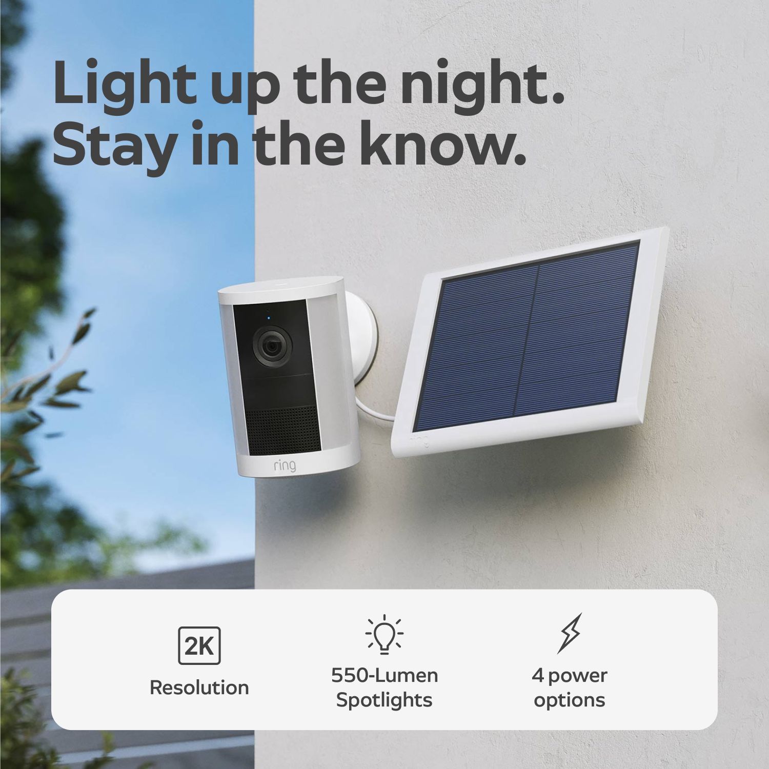 Spotlight Cam 2K - Solar:White Ring outdoor camera with spotlight mounted on a wall beside a white-framed solar panel, under text promoting 2K, 550 lumens, 4 power options.