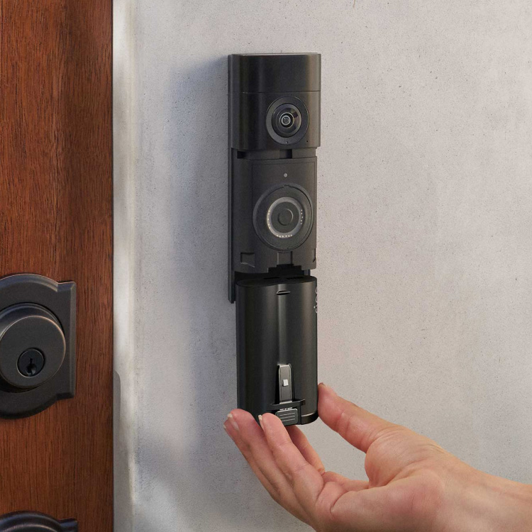 Quick Release Ultra Battery Pack being inserted into Ring Battery Doorbell Plus mounted on a wall next to a door.