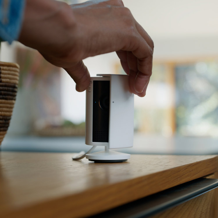 Close-up of hands closing the manual removable privacy cover on a white Indoor Cam Plus.
