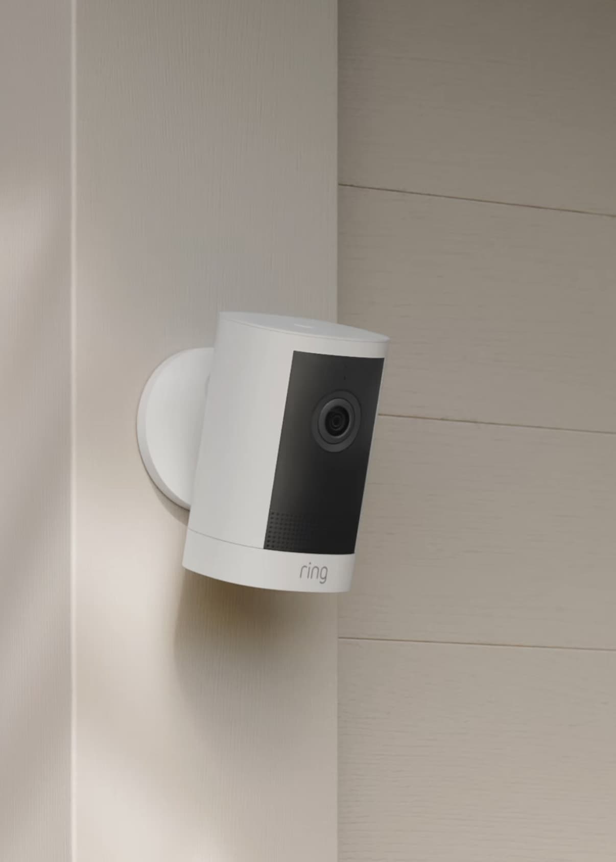 Outdoor Cam (2nd Gen) security camera mounted on a beige exterior wall, angled slightly downward with a black lens panel.