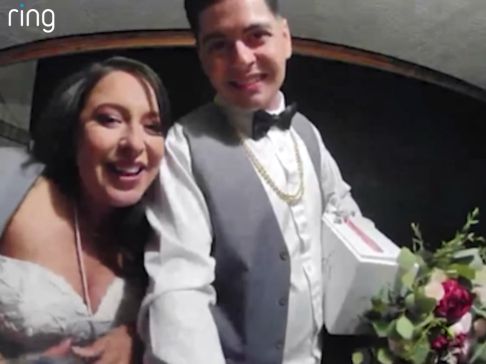 Married couple smiling and posing in front of doorbell coming home from their reception