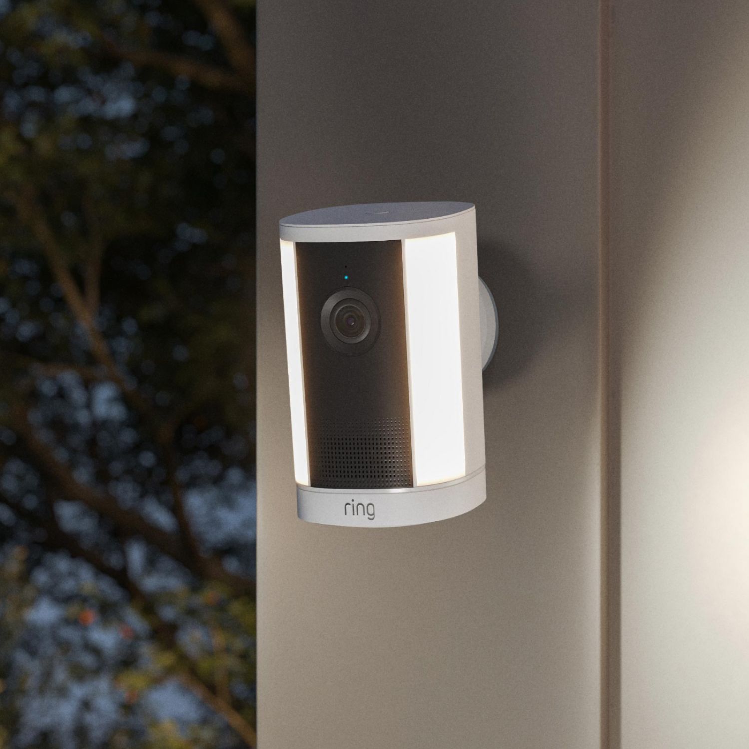 Spotlight Cam 4K Plus - Power over Ethernet:Outdoor mounted Ring Spotlight camera with dual vertical LED lights glowing at dusk, lens centered on a black panel.