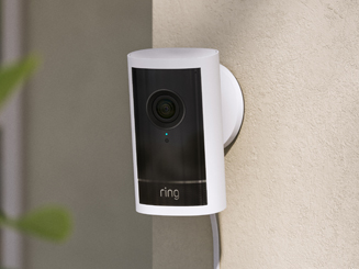 White Outdoor Cam Pro  mounted to beige wall with plug-in cord running down wall