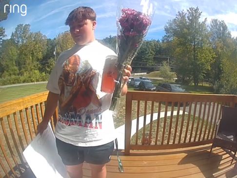 Boy at doorbell holding flowers and poster sign to ask out someone to homecoming dance