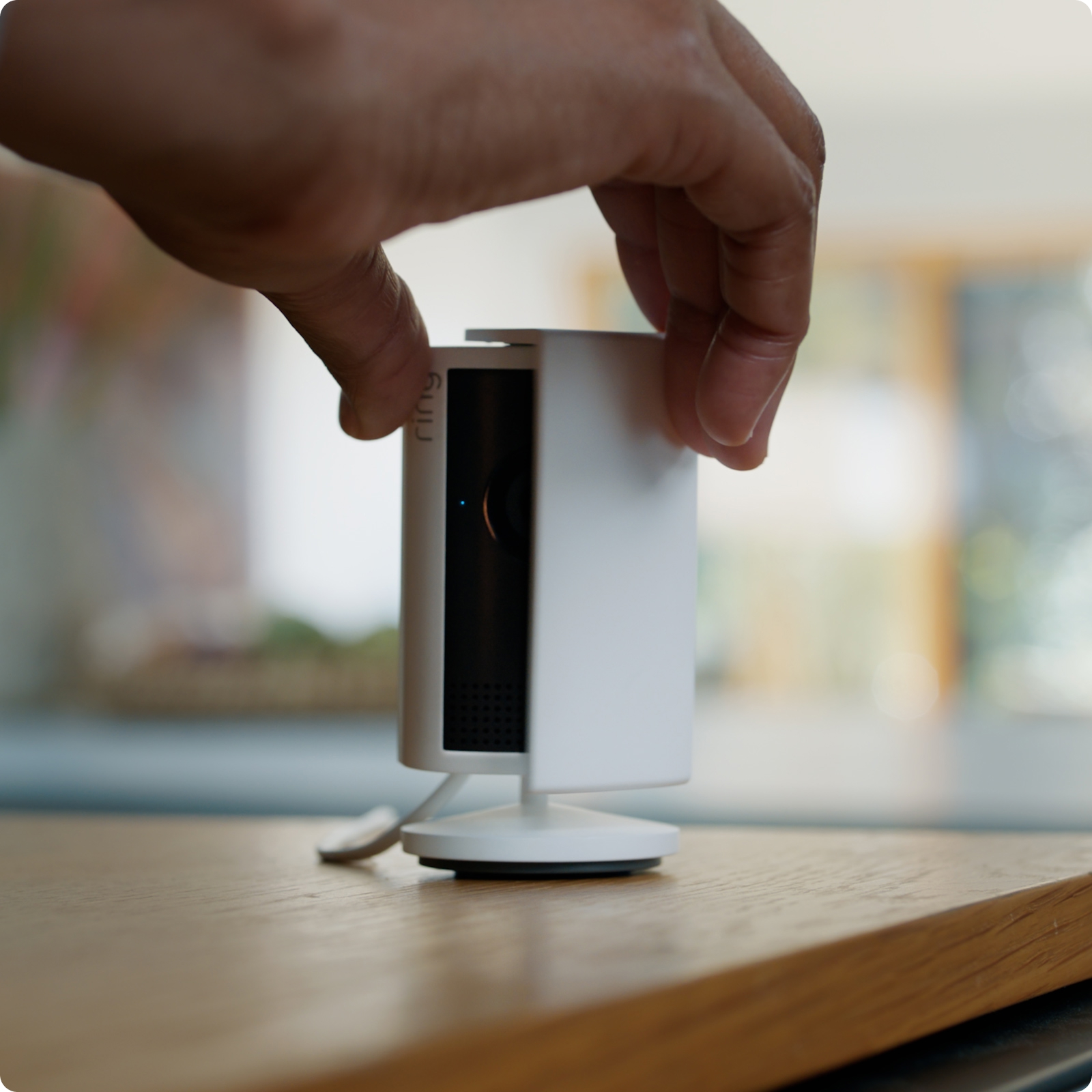 Close-up of hands closing the manual removable privacy cover on a white Indoor Cam Plus.
