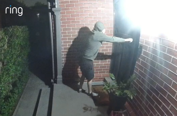 A person in a green hoodie and hand over their face approaches a home and tries to open the door. He then checks the side door and is deterred by the automatic outdoor lights, and runs away.  All recorded on the Outdoor Camera Plus featuring retinal 2K.