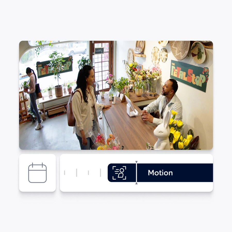 A woman is greeted by a business owner behind his front counter. Ring app interface below showing this event on a timeline. 