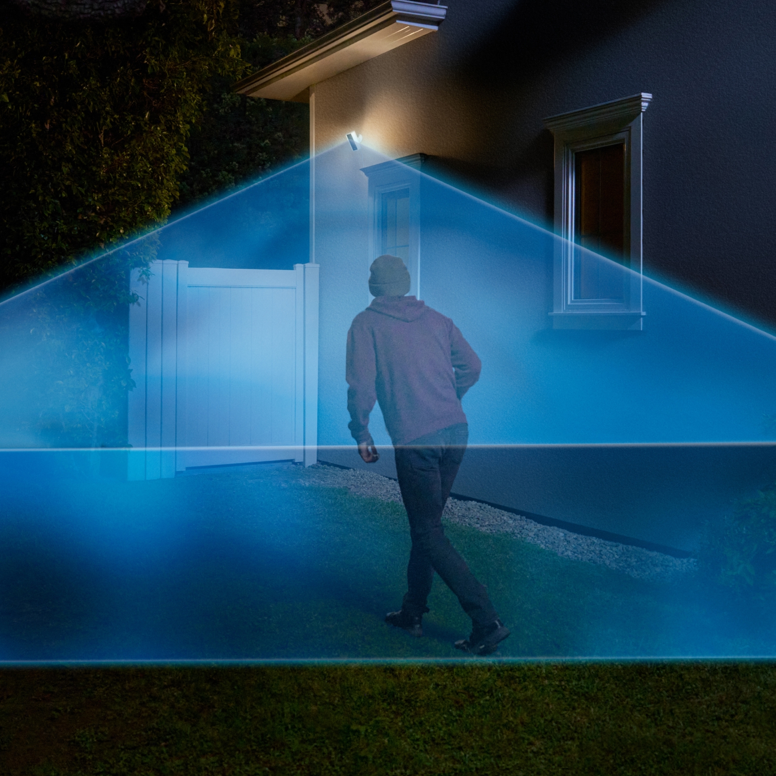 A thief walks into a driveway covered in a blue laser graphic extending out from a Ring Spotlight Camera Pro mounted to the house.