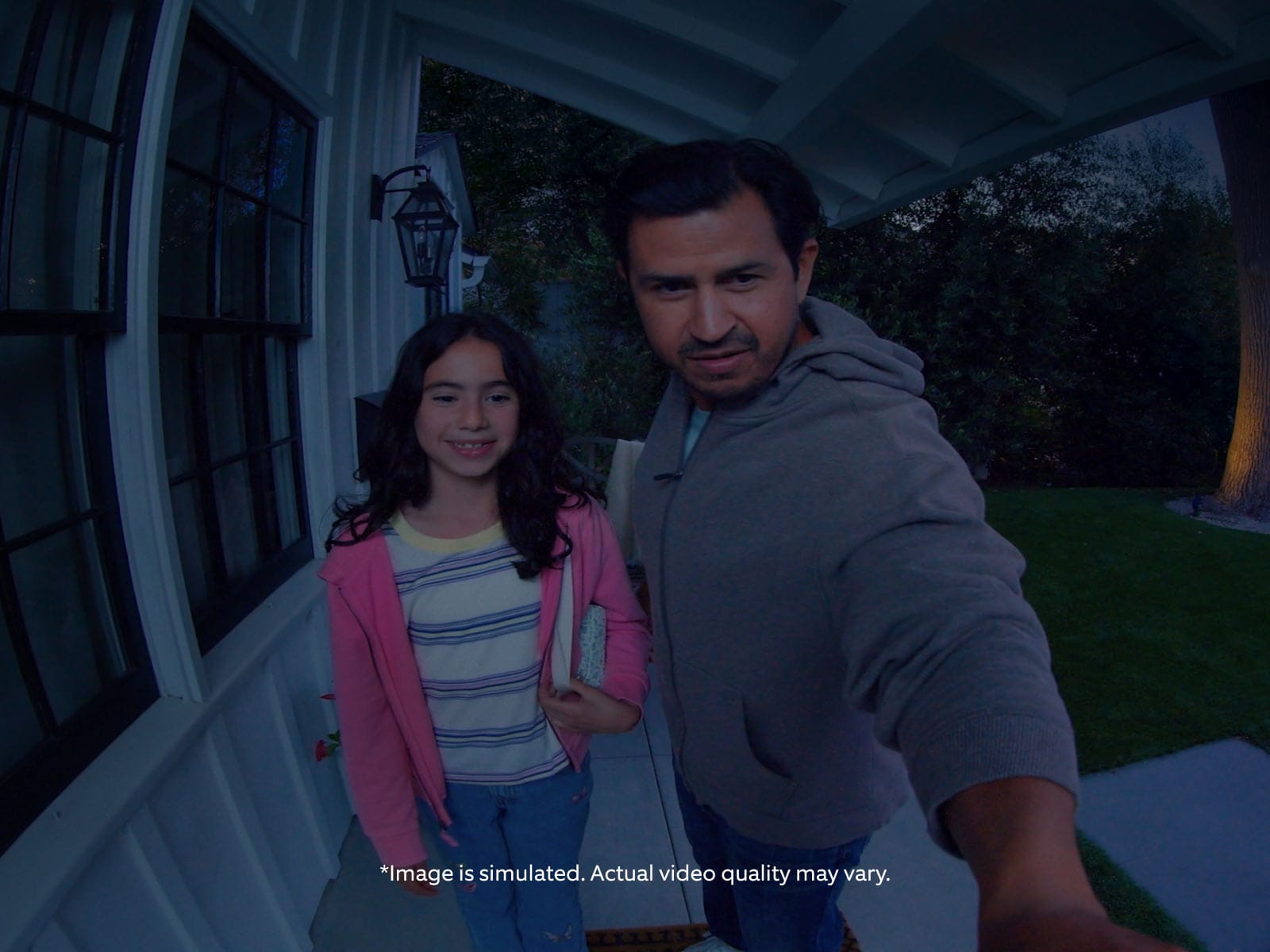 A daughter on the left in a pink sweater and blue jeans and a father on the right in a brown jacket and blue jeans stand outdoors in front of a house door at night with keys in hand. The scene is well-lit, showing clarity even at night. 