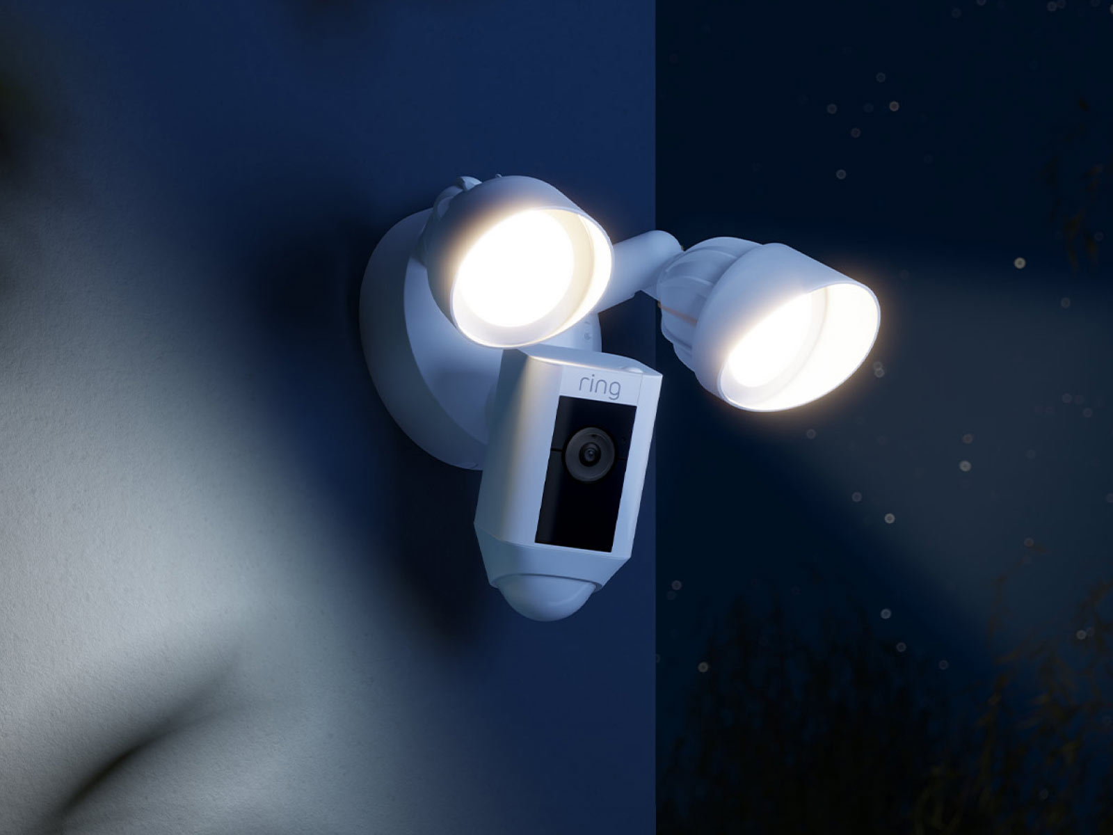 White Ring Floodlight Cam mounted outside on a dark night, with the lights illuminated.