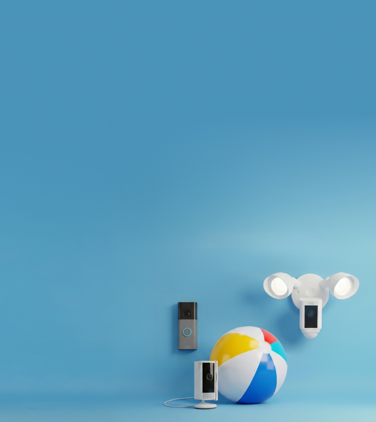 Smart home devices against a blue backdrop: a video doorbell, a plug-in indoor camera, and a white floodlight camera beside a beach ball.
