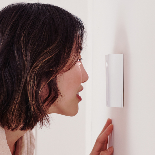 Asian woman looking through ring peephole camera