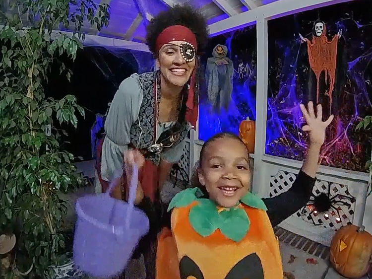 A mom and her son dressed in Halloween costumes waving at the doorbell camera.