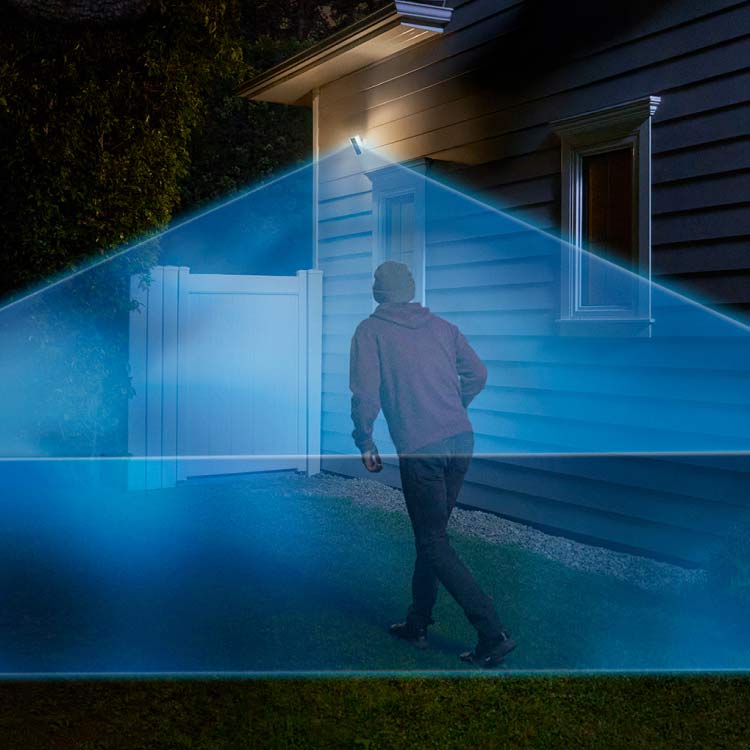 Delivery man walks into a driveway covered in a blue laser graphic extending out from a Ring Outdoor Cam Pro mounted to the house.