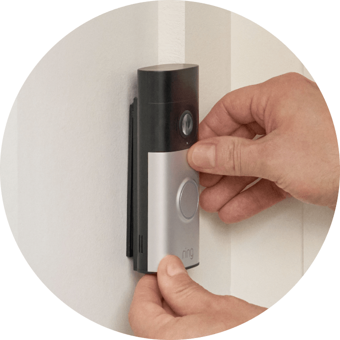 Close-up of hands securing a Wired Doorbell Plus (2nd Gen) onto its mounting bracket. 