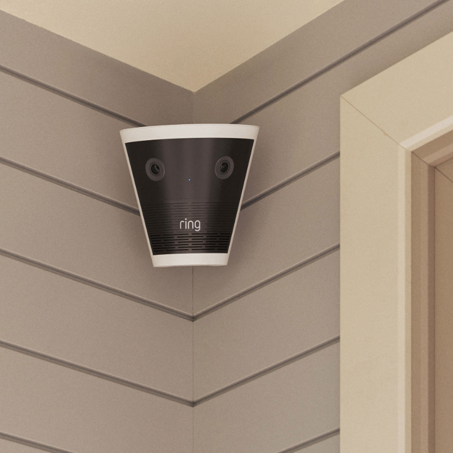 Ring Elite 140 4K - Corner-mounted Ring indoor camera with dual lenses and LED indicator on a gray shiplap wall near a doorway.