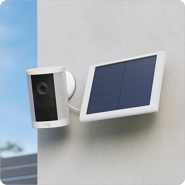 Spotlight Cam (2nd Gen) mounted on a wall beside a solar panel under a clear sky.
