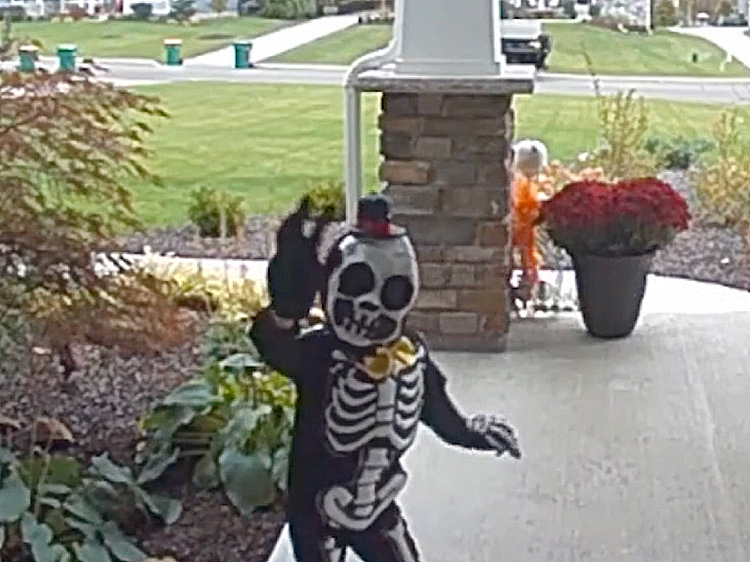 A young boy in a skeleton costume waving the camera.