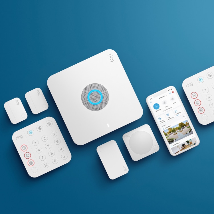 Alarm Pro Security Kit components, including a base station, keypad, sensors, and a smartphone displaying the Ring app, arranged on a blue background.