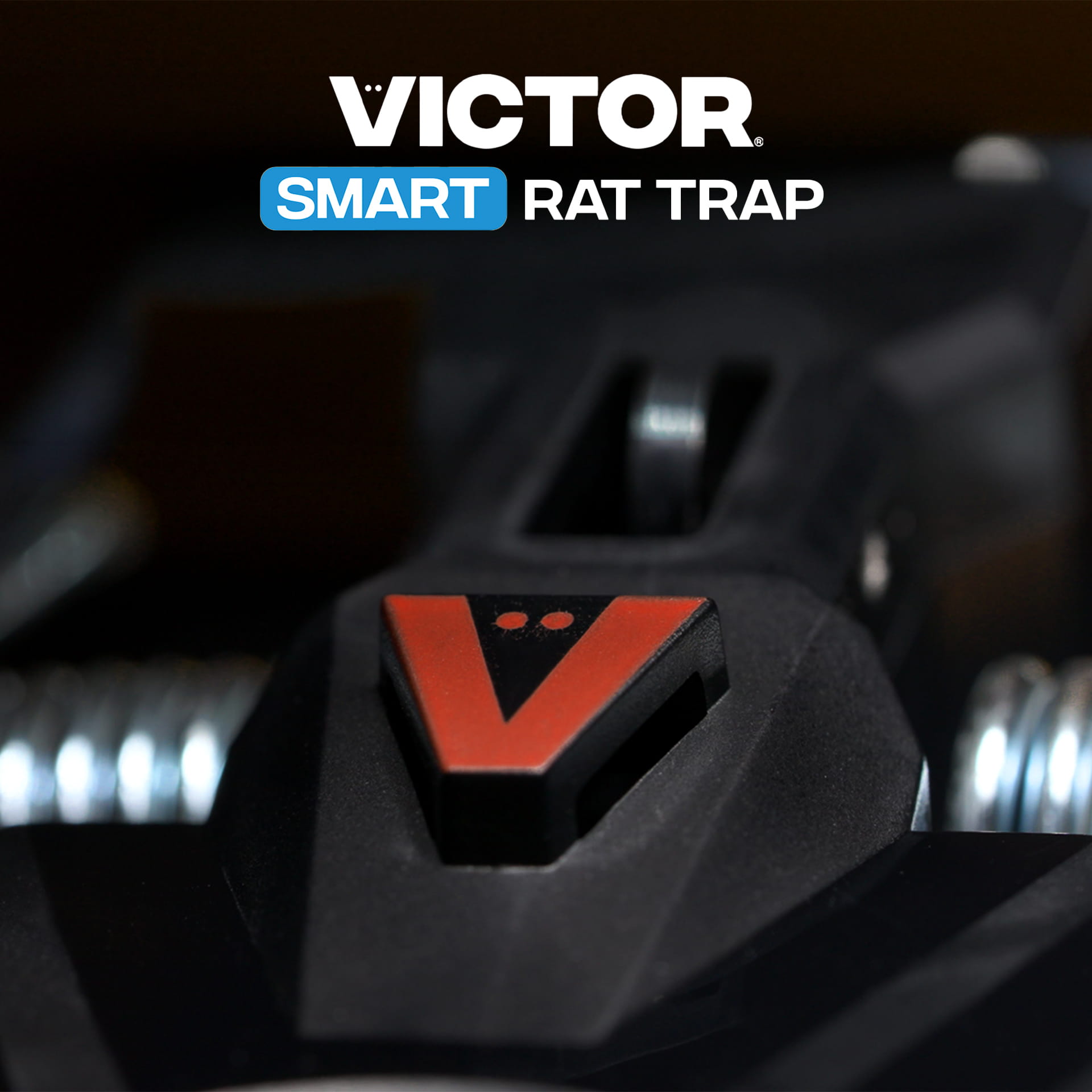 Victor® Smart Rat Trap, Indoor Snap Trap  - Close-up of a Victor Smart Rat Trap, showing the red V logo on a black device with metal springs in soft focus.