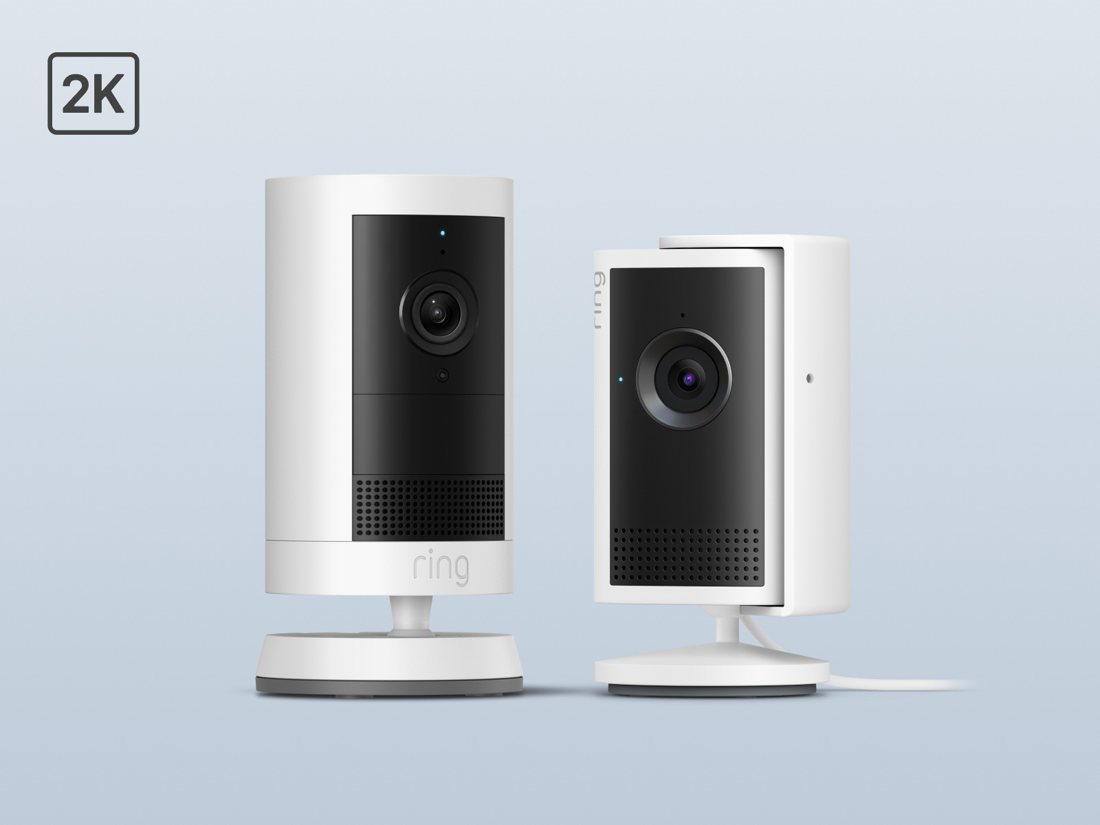 Two white indoor security cameras on stands with black front panels and blue status LEDs, labeled 2K, against a light gray background.