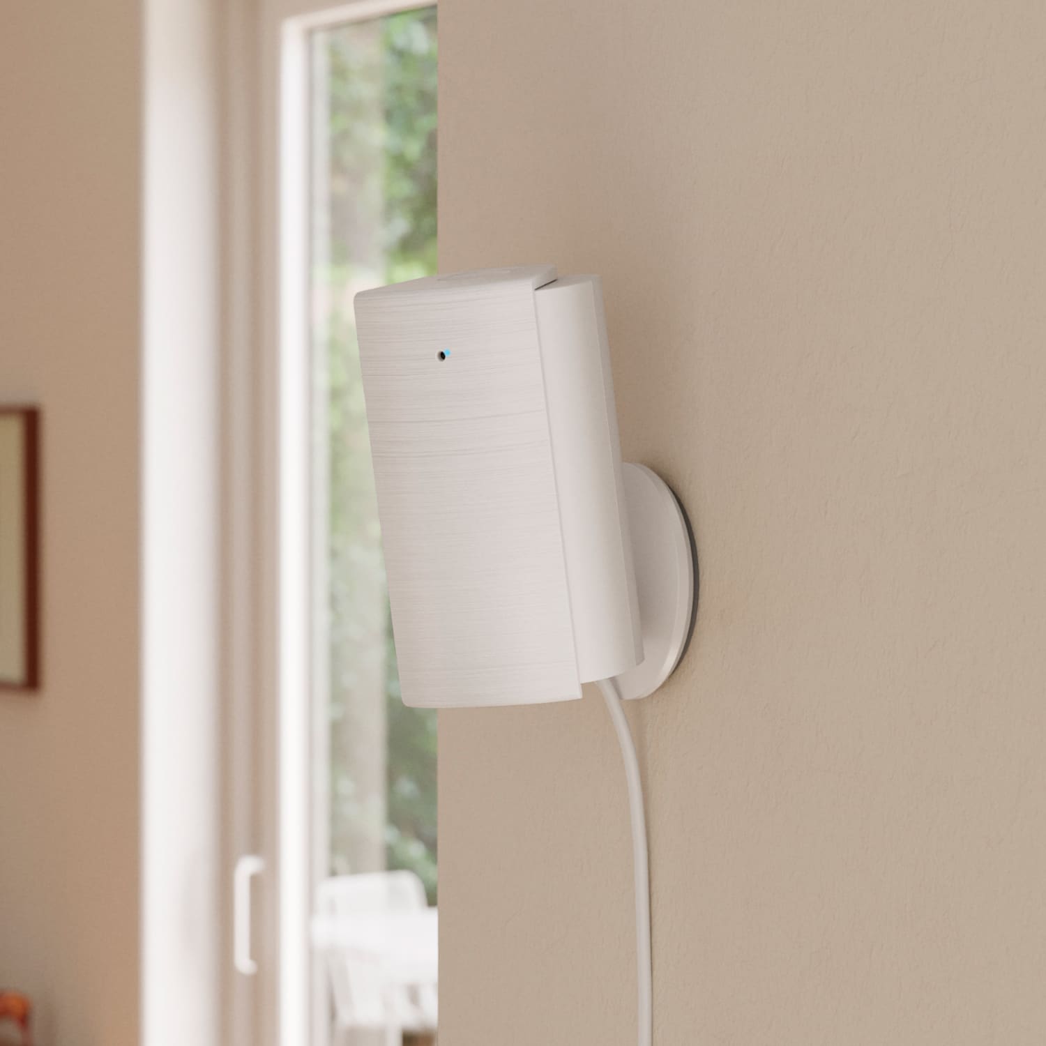 Indoor Cam 4K - White Indoor Cam 4K and power cable, installed near a bright window in a modern home interior.