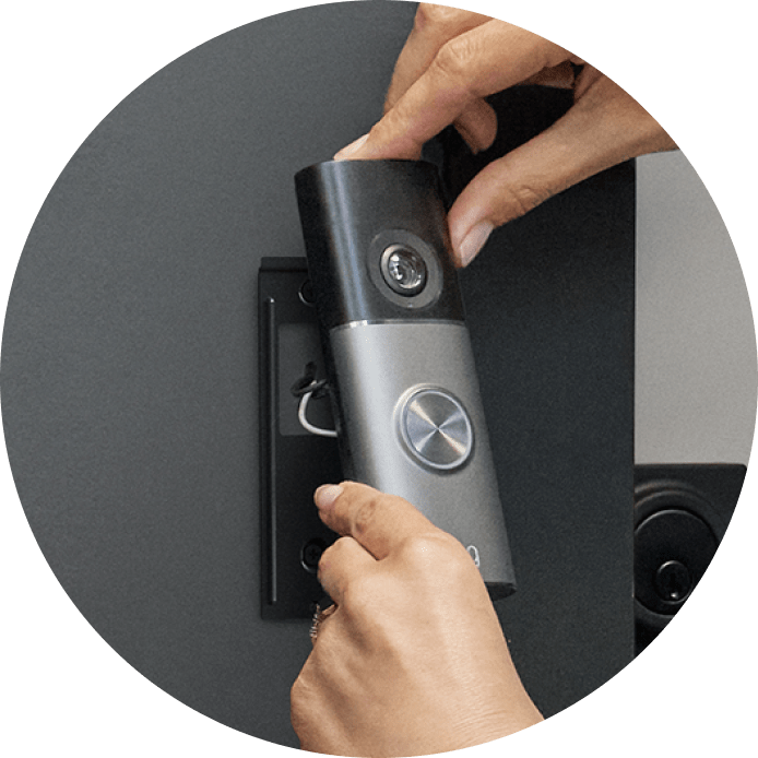 Close-up of hands securing a Wired Doorbell Pro (2nd Gen) onto its mounting bracket. 