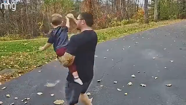 A man holds a young boy up to a Ring camera so he can say hello to his mom.