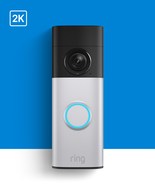 Ring doorbell camera with 2K resolution, silver and black design with blue illuminated button on bright blue background.