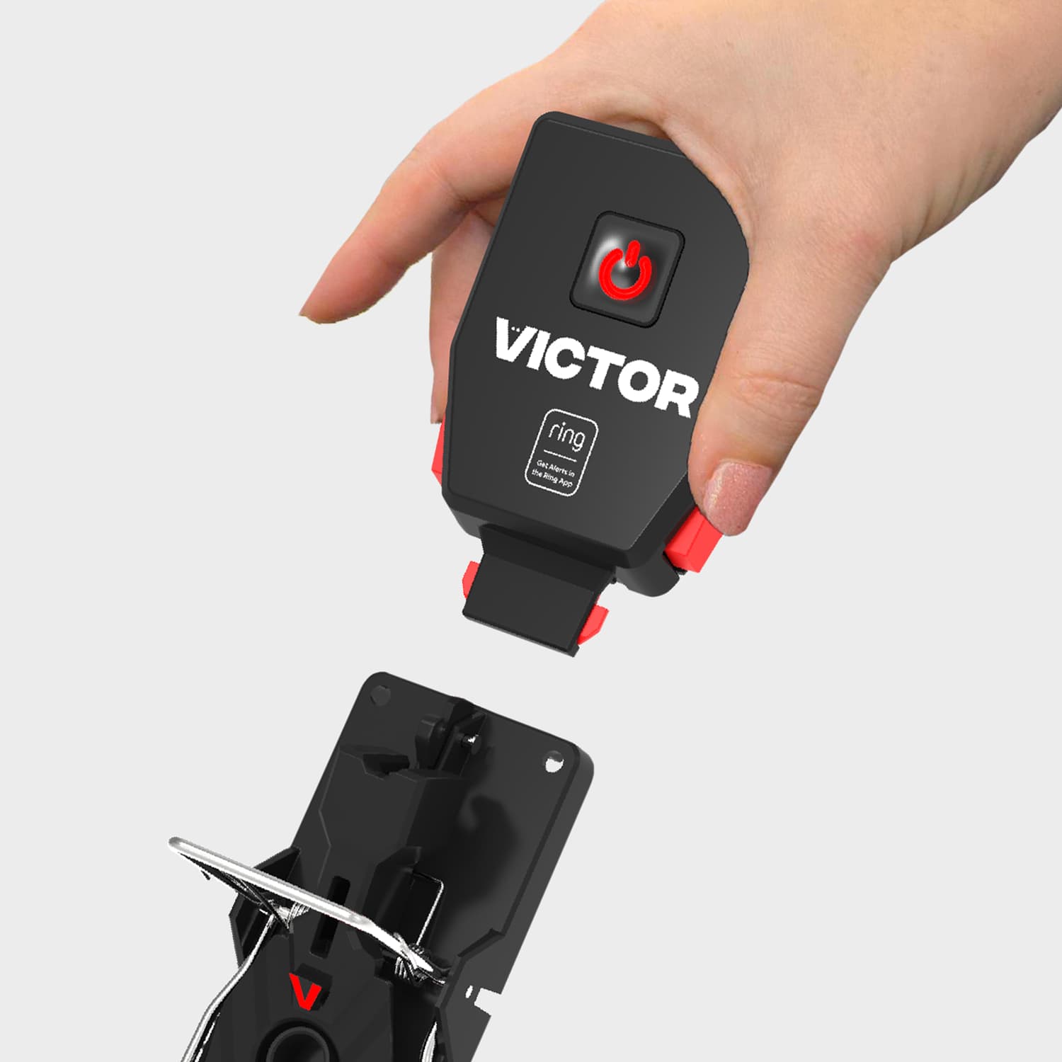 Victor® Smart Mouse Trap, Indoor Snap Trap - Hand holding a black Victor device with red power button, aligning it above a matching black mount against a light gray background.