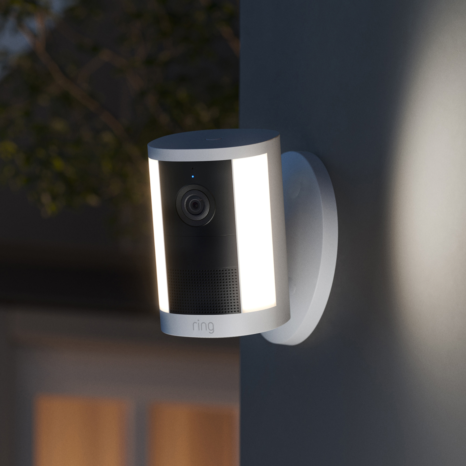 Spotlight Cam (Newest Model) - Wired:White Ring Spotlight Cam (2nd Gen) mounted to a wall with mounted hardware connected on a gray wall.