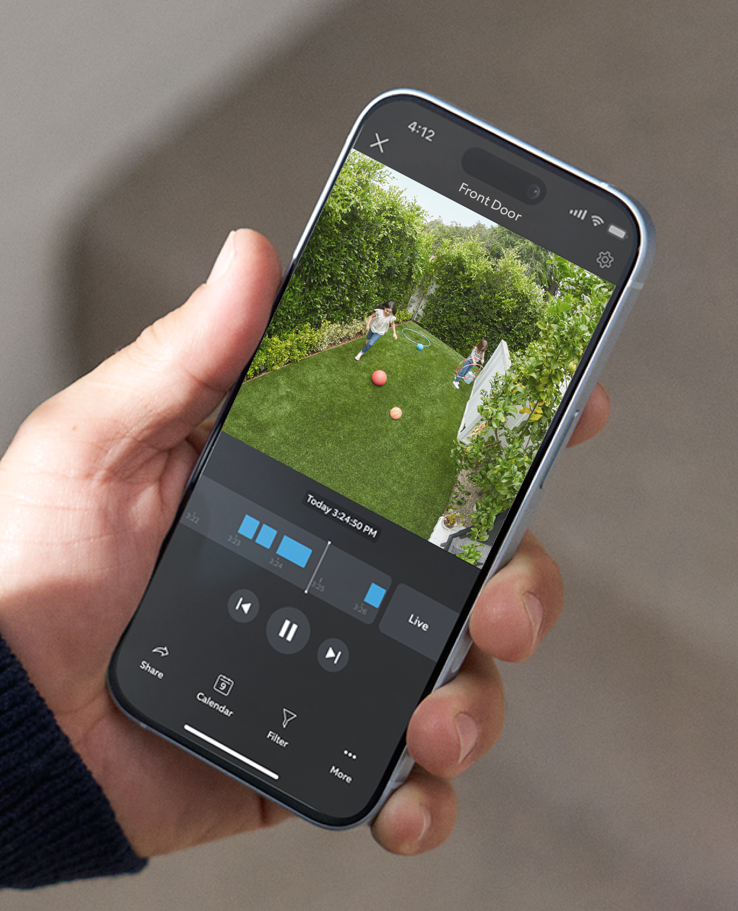 Hand holding Phone with Ring App open showing a backyard recording