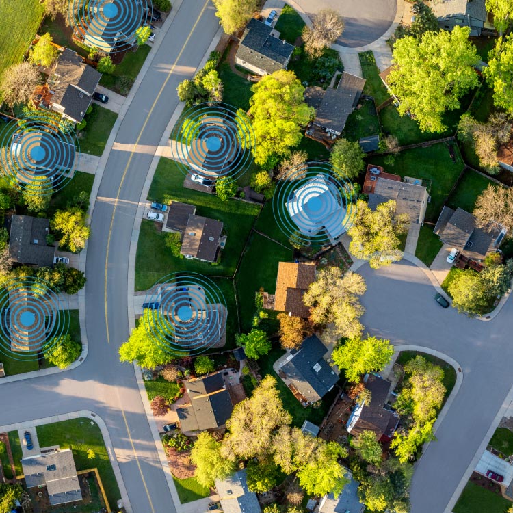 Aerial view of neighborhood with circular signal indicators showing Amazon Sidewalk connectivity between Ring devices across homes.