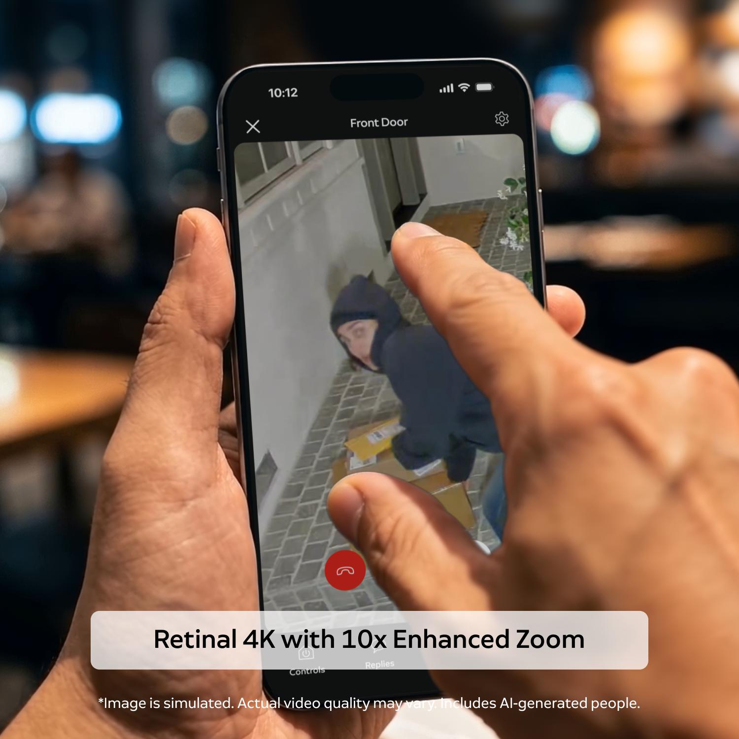 Spotlight Cam 4K Plus - Hands holding a smartphone showing a front door camera view; a hooded figure near packages on a tiled porch, with pinch-to-zoom gesture.