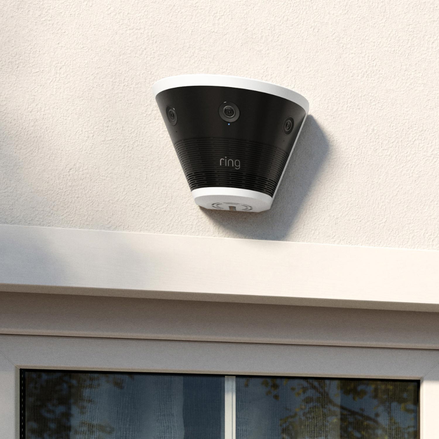Ring Elite 180 4K - Black and white Ring cone-shaped outdoor camera mounted above a window on a light stucco wall, shown in daylight.