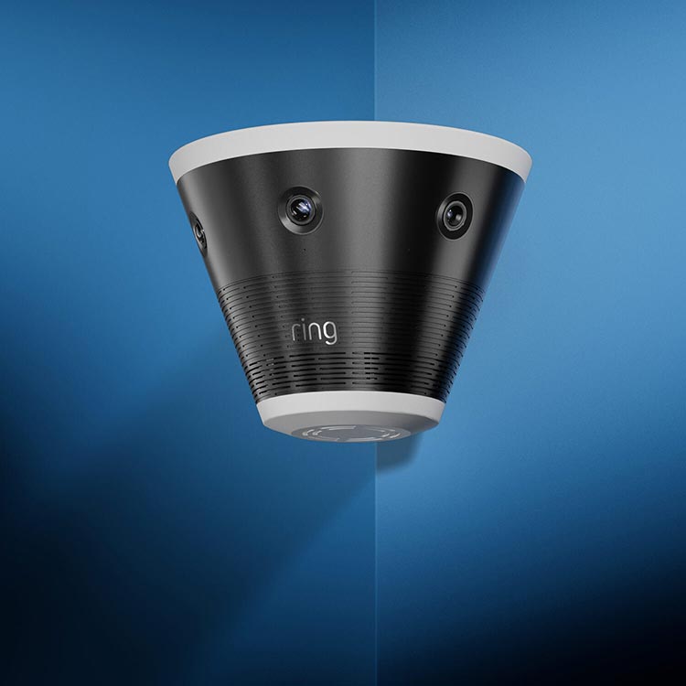 Black and white Ring security camera with multiple lenses mounted on a wall against a blue background.