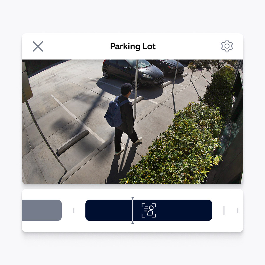 A screen showing a video recording of a man with a backpack walking along a sidewalk. The top of the video says 