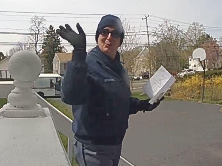 A mailwoman reads a heartfelt note while waving at the camera.