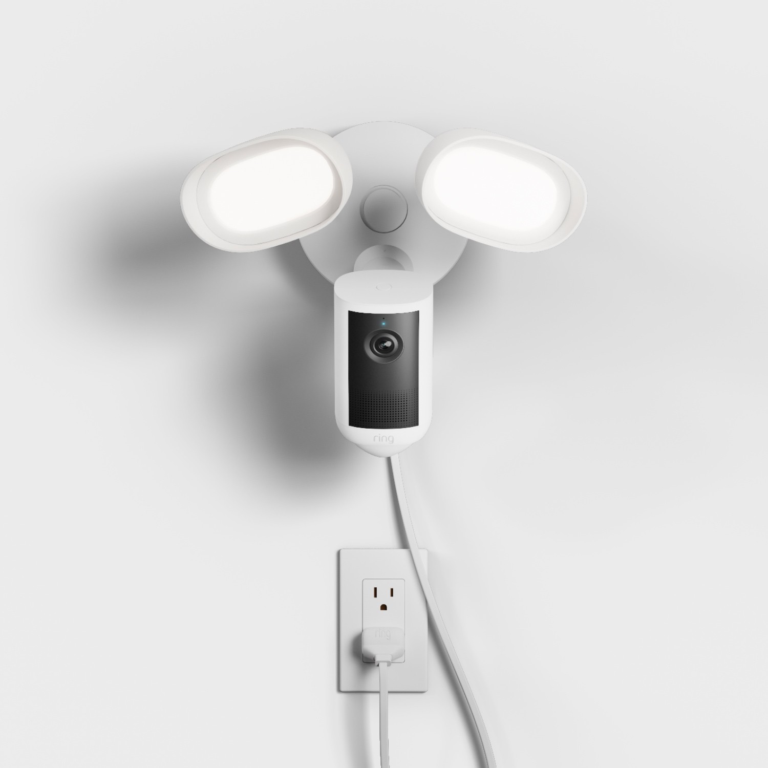 Floodlight Cam 4K Plus - Plug-In:White wall-mounted floodlight with two bright oval LEDs and a central camera unit, plugged into a nearby outlet via a white cord.